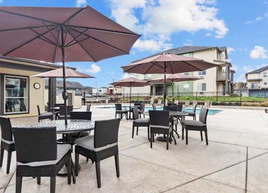 A patio with tables and chairs under umbrellas.
