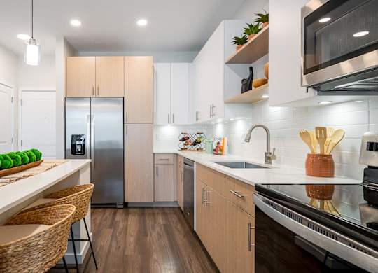 A modern kitchen with wooden floors and stainless steel appliances.