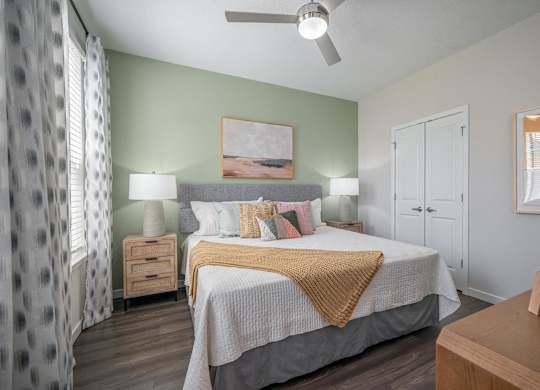 A bedroom with a bed, nightstands, and a ceiling fan.