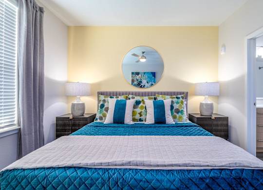 A bed with a blue comforter and a white pillow is in the center of the image.