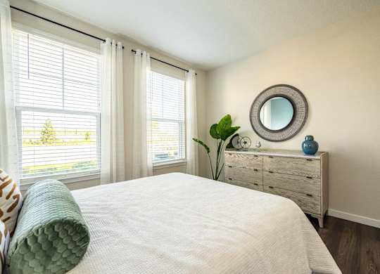 A bedroom with a large bed, a dresser, and a mirror.