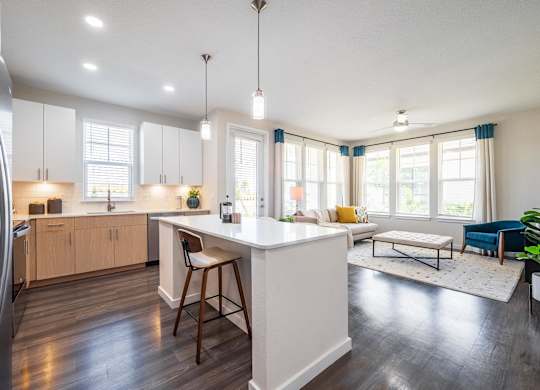 A modern kitchen with a white island and wooden floors.