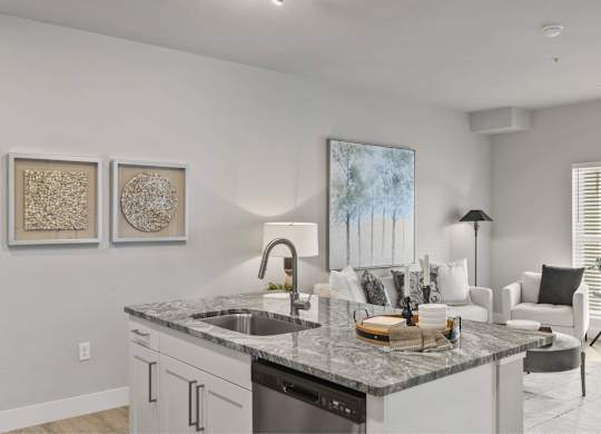 A modern kitchen with a marble countertop and white cabinets.