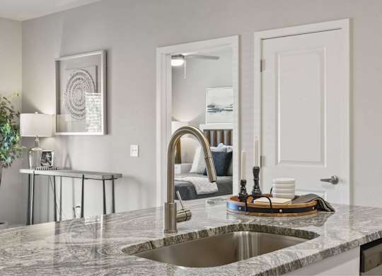 A modern kitchen with a marble countertop and a stainless steel sink.