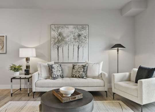 A living room with a white couch, a grey coffee table, and a painting on the wall.