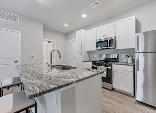 A kitchen with a marble countertop and stainless steel appliances.