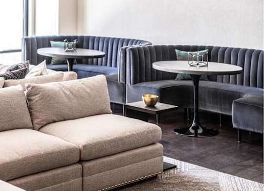A modern living room with a large sofa, a round table, and a hanging light fixture.