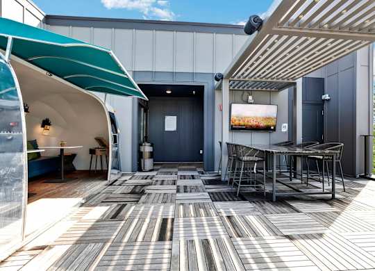 A patio with a table and chairs under a striped awning.