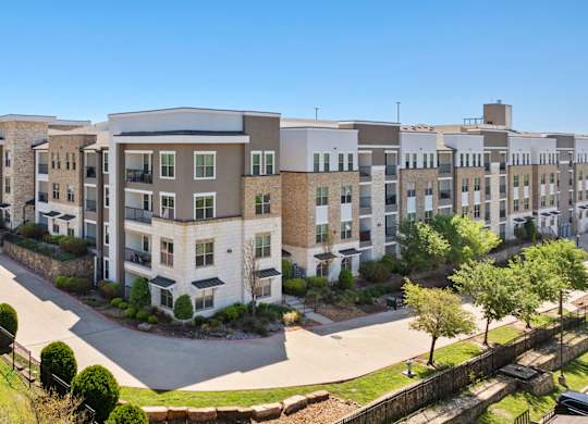 A large apartment complex with a parking lot in front.