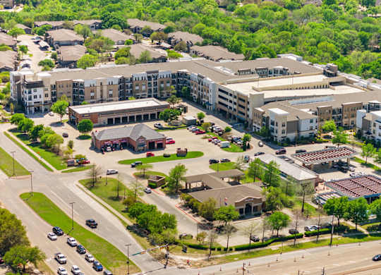 A large apartment complex with a parking lot in front.