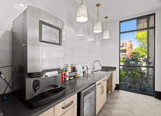 A modern kitchen with a large window overlooking a tree.
