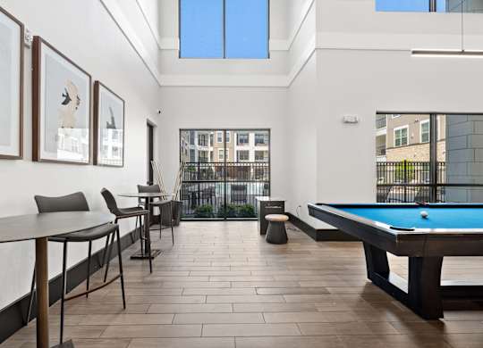 A room with a pool table and a view of the city.