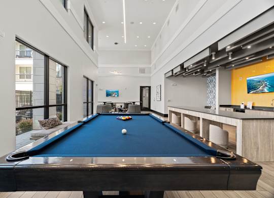A pool table in a room with a bar area.