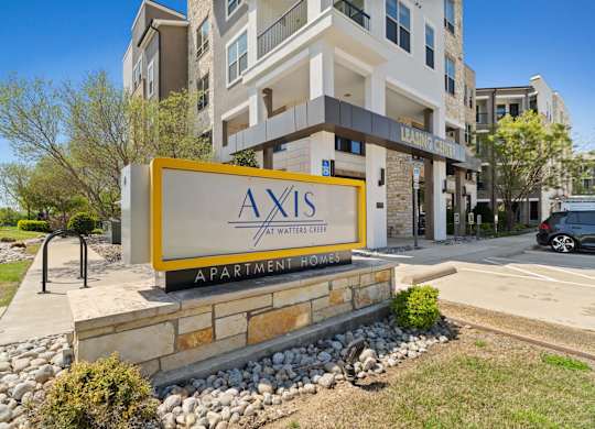 A sign for Axis Apartments in front of a building.
