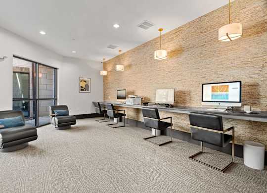 A modern office space with a brick wall and a long desk with chairs.