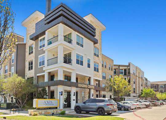 A modern apartment building with a leasing sign in front.