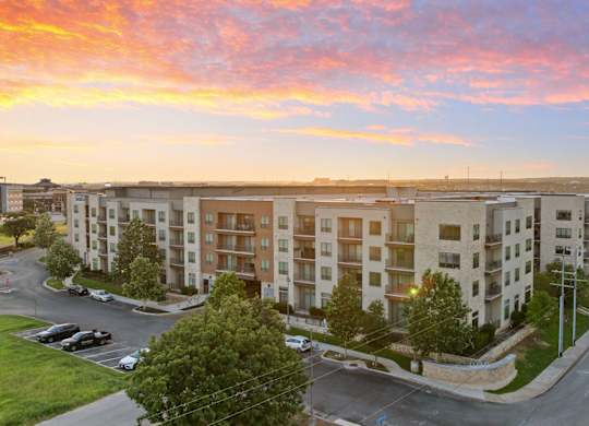A sunset view of a street with apartment buildings on the side.