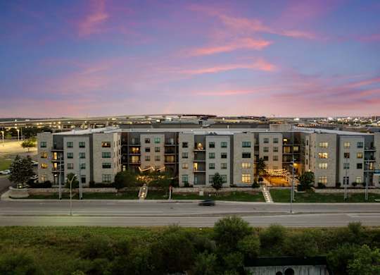 A large apartment complex is shown with a beautiful sunset in the background.