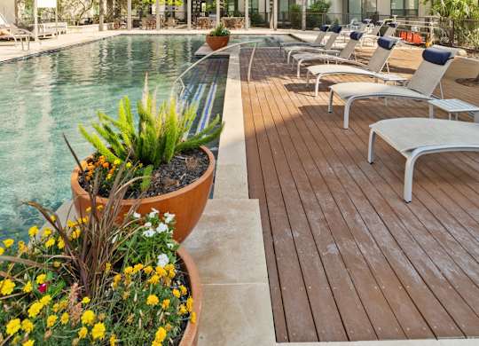 A pool area with chairs and a building in the background.
