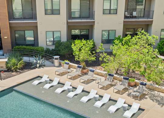 A large swimming pool surrounded by sun loungers and chairs.