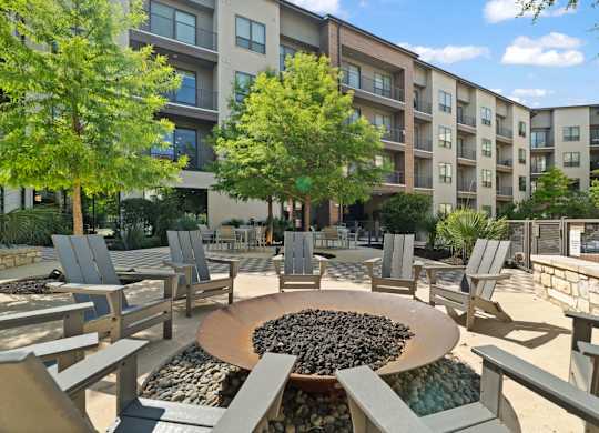 A large circular fire pit sits in the middle of a patio surrounded by chairs.