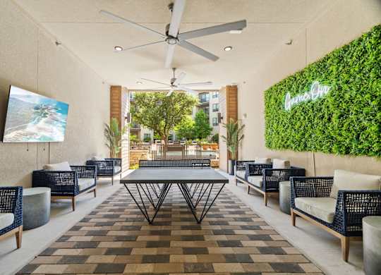 A patio with a table, chairs, and a green wall with the word