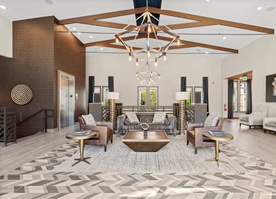 A large, open living room with a wooden floor and a chandelier hanging from the ceiling.