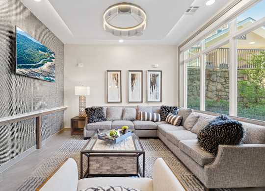 A modern living room with a grey couch, a coffee table, and a large painting on the wall.