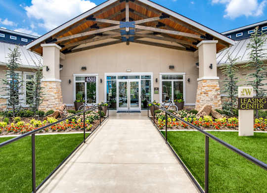The image shows the front of a leasing center with a clear blue sky in the background.