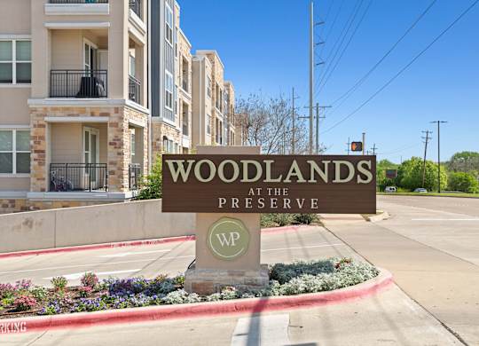 A sign that says Woodlands at the Preserve in front of some buildings.