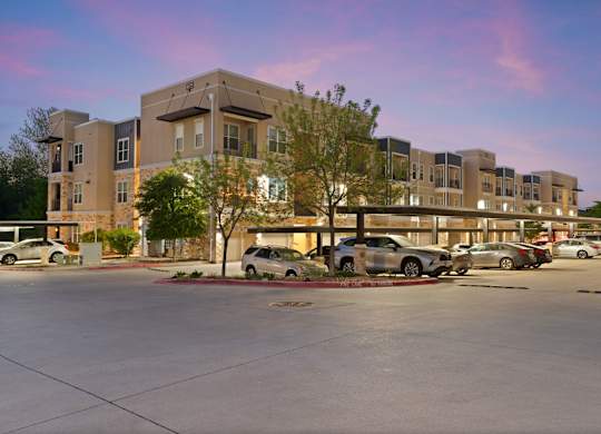 A parking lot in front of a building with cars parked.