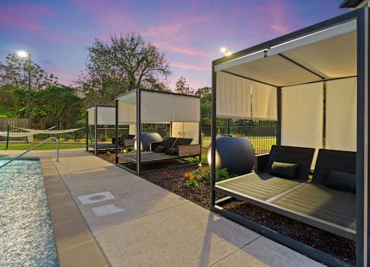 A poolside lounge area with a sunshade and a water feature.