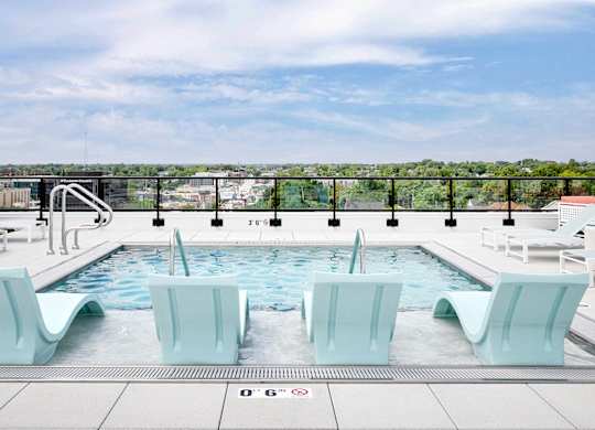 A pool with four chairs and a white railing.