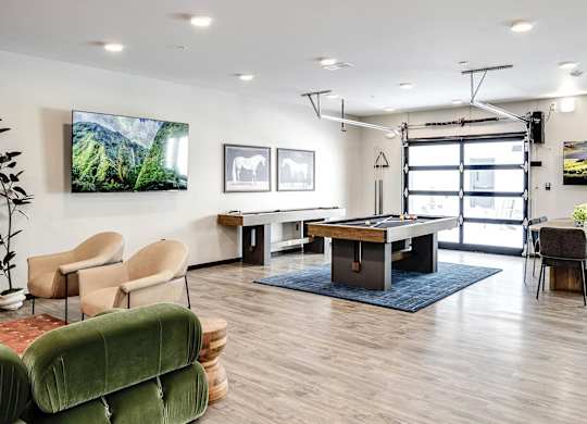 A room with a table, chairs, and a TV on the wall.