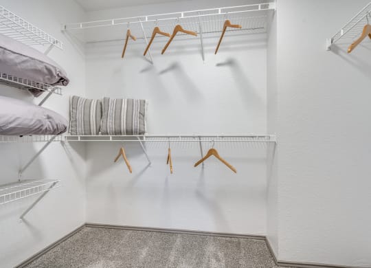 a walk in closet with a white wall and a rack with hangers