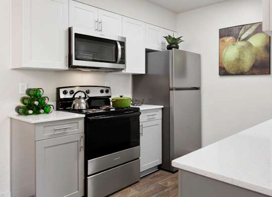 A modern kitchen with white cabinets and stainless steel appliances.