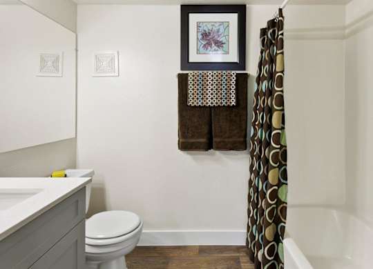 A bathroom with a toilet, sink, and a picture hanging on the wall.