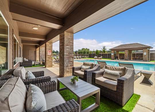 A patio with a table and chairs overlooking a pool.