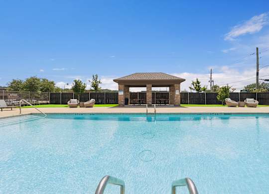 A swimming pool with a gazebo-like structure in the middle.