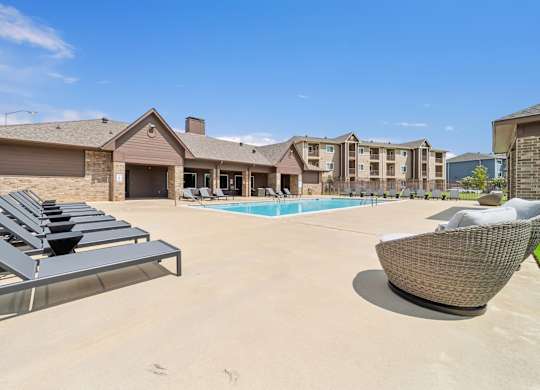 A sunny day at the poolside with lounge chairs and a building in the background.