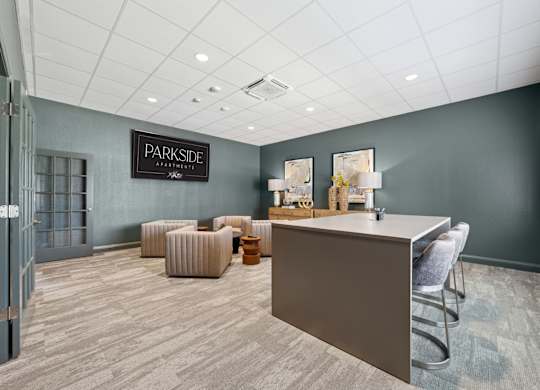 A reception area with a desk and chairs in a room with a grey wall and a door.