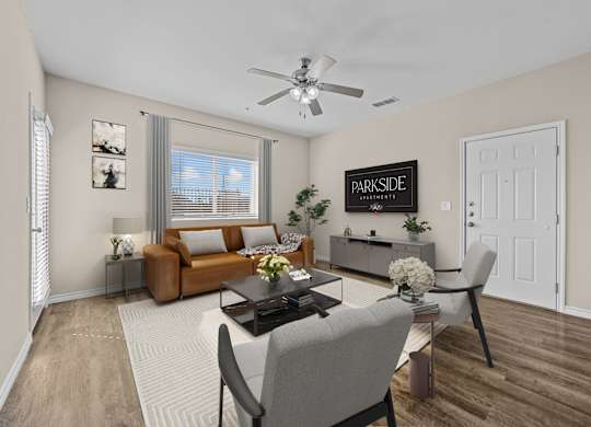 A living room with a brown couch, a coffee table, and a ceiling fan.
