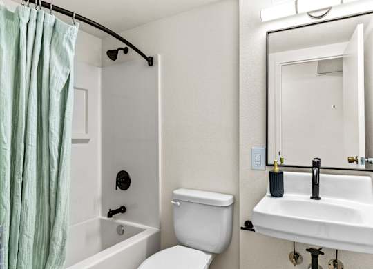 A white bathroom with a toilet, sink, and shower.