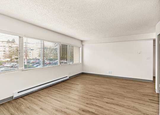 A room with wooden flooring and a window with blinds.