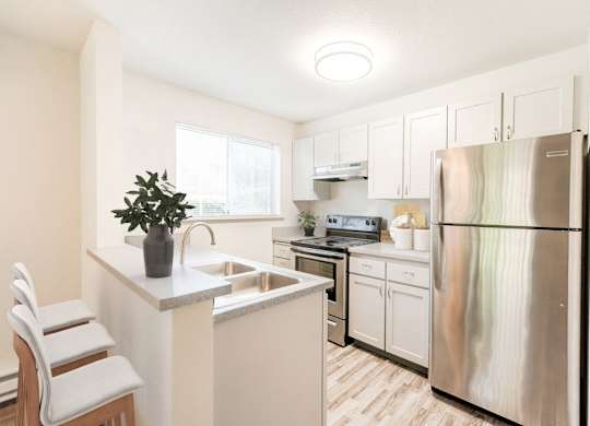 A kitchen with a white refrigerator and white cabinets.