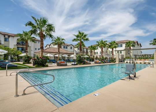 A swimming pool surrounded by palm trees and apartment buildings.