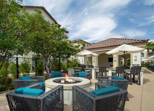 A patio with a fire pit and chairs.