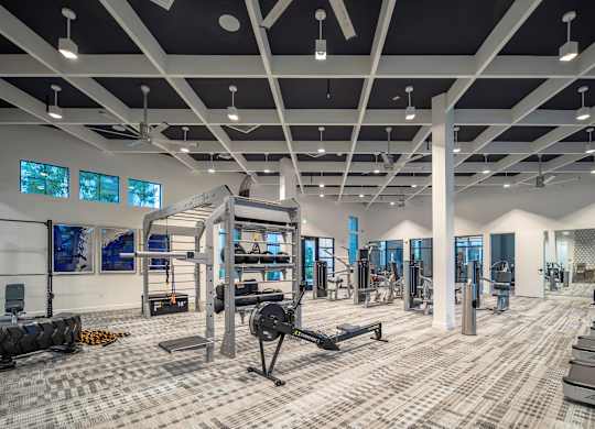 A spacious gym with a variety of equipment and a person working out.