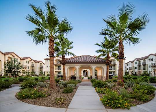 A beautifully landscaped entrance to a residential complex with palm trees and a central archway.