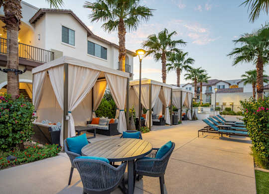 A patio with a table and chairs is surrounded by palm trees.